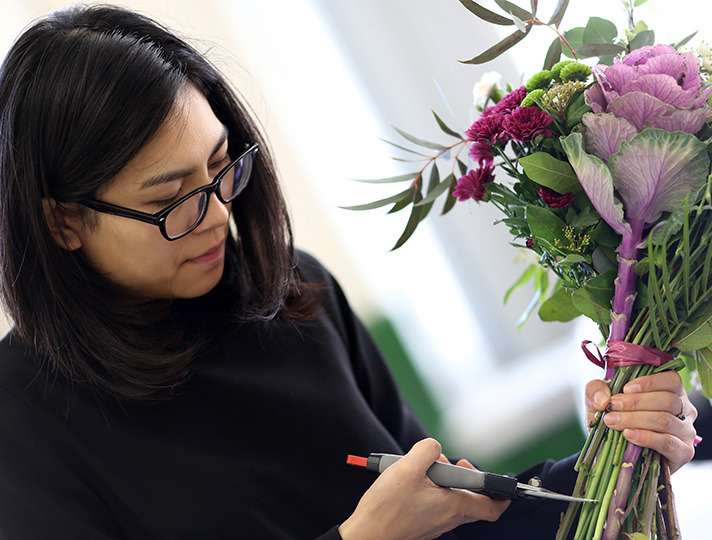 Student creating a bouquet of purple flowers